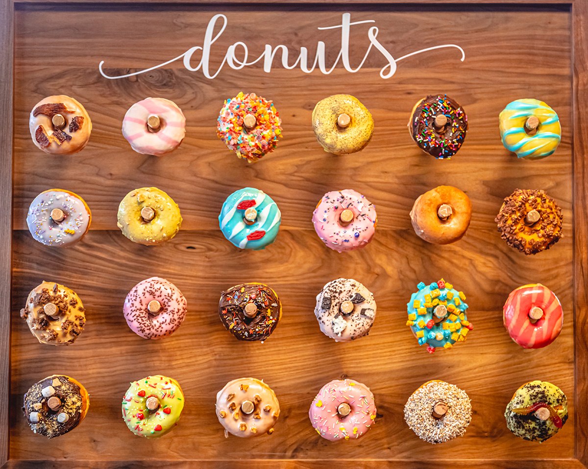 An assortment of decorated donuts displayed on a wooden donut wall